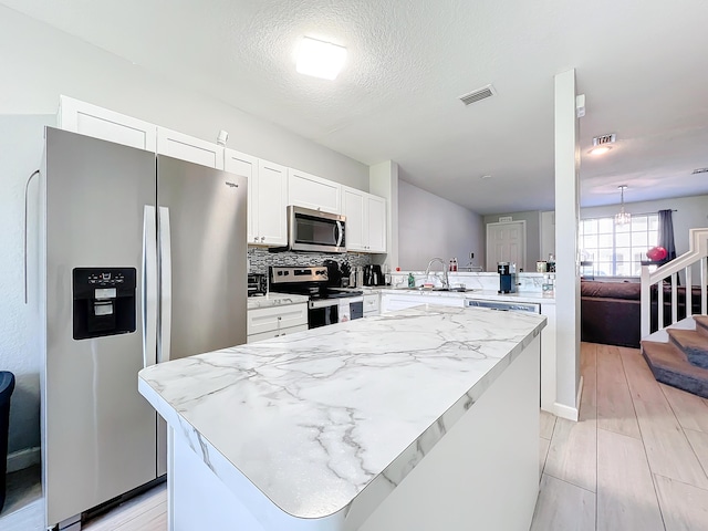 kitchen featuring white cabinetry, sink, decorative backsplash, kitchen peninsula, and stainless steel appliances