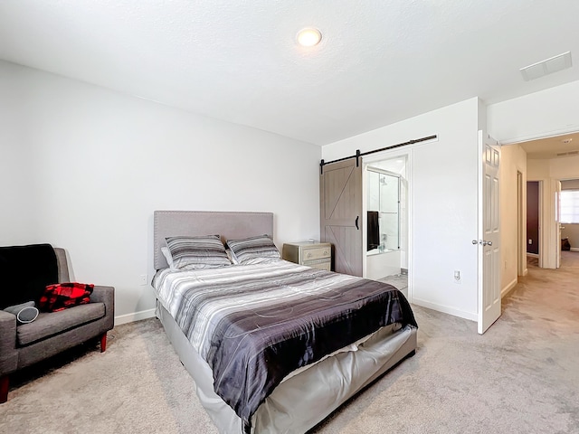 carpeted bedroom with ensuite bathroom, a barn door, and a textured ceiling