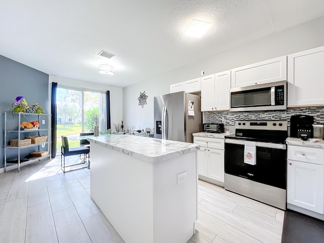 kitchen with white cabinetry, decorative backsplash, a center island, and appliances with stainless steel finishes