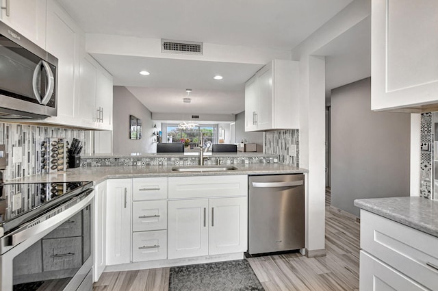 kitchen featuring stainless steel appliances, white cabinetry, sink, and kitchen peninsula