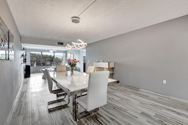 dining area featuring a notable chandelier, a textured ceiling, and light hardwood / wood-style flooring