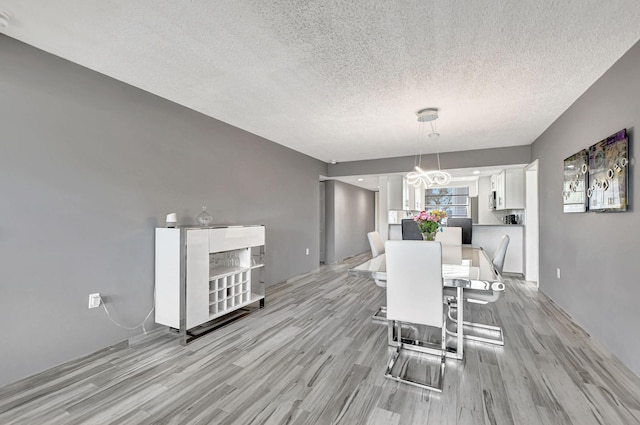 unfurnished dining area featuring light hardwood / wood-style floors, a chandelier, and a textured ceiling