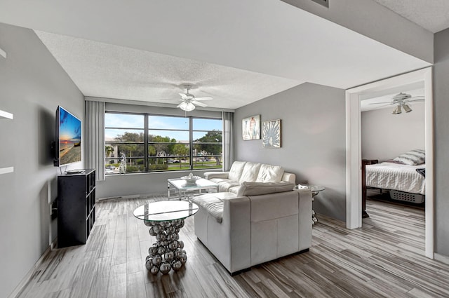 living room with ceiling fan, light hardwood / wood-style floors, and a textured ceiling