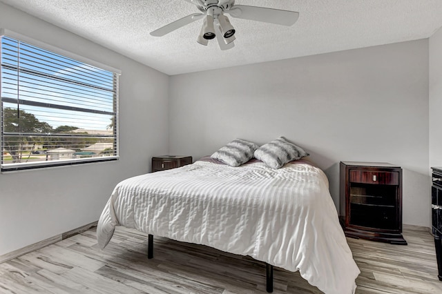 bedroom with ceiling fan, light hardwood / wood-style flooring, and a textured ceiling