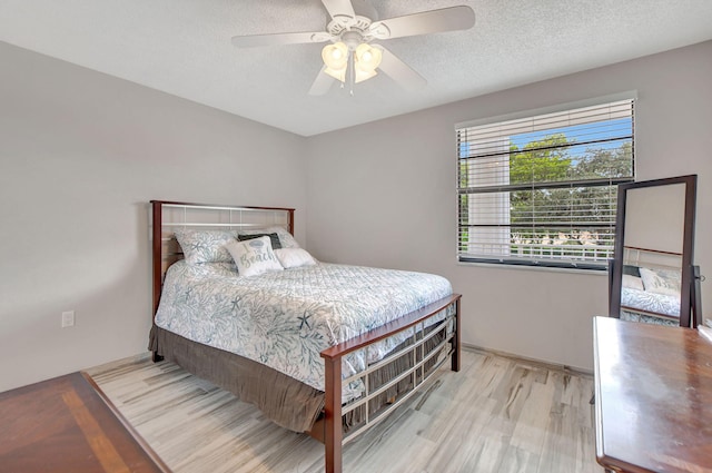 bedroom with ceiling fan, light hardwood / wood-style flooring, and a textured ceiling