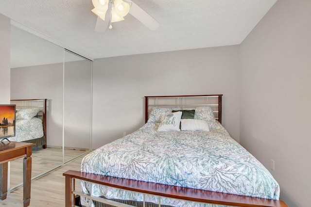 bedroom with hardwood / wood-style flooring, ceiling fan, a textured ceiling, and a closet