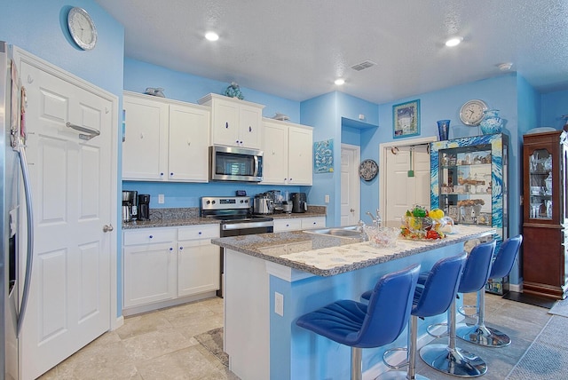 kitchen with appliances with stainless steel finishes, a sink, visible vents, and white cabinets