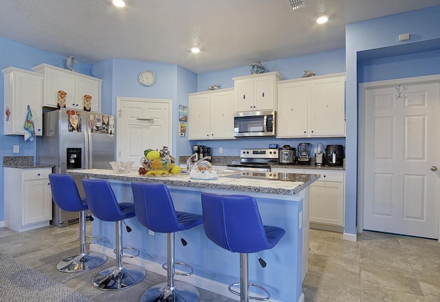 kitchen with appliances with stainless steel finishes, a breakfast bar, and white cabinetry