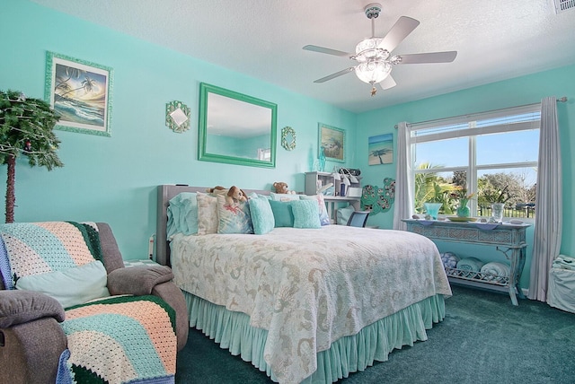 bedroom featuring visible vents, dark carpet, a textured ceiling, and ceiling fan