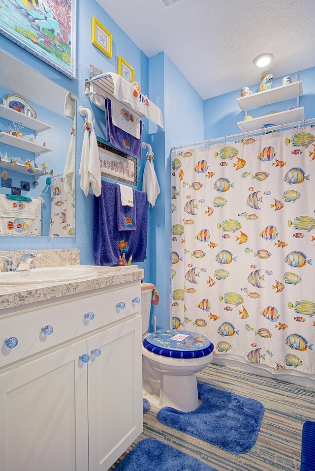 bathroom with vanity, a textured ceiling, and toilet