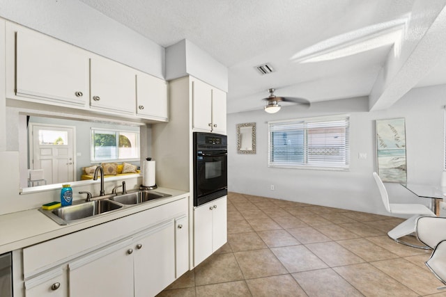 kitchen featuring light tile patterned flooring, black oven, white cabinetry, sink, and ceiling fan