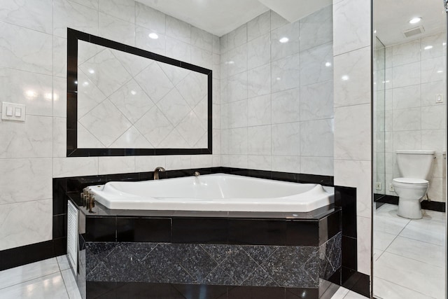 bathroom with tile patterned floors, toilet, tile walls, and tiled tub