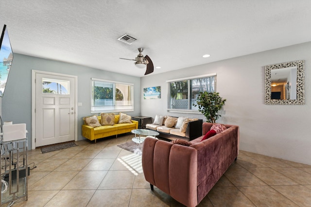 living room with ceiling fan, light tile patterned floors, and a textured ceiling