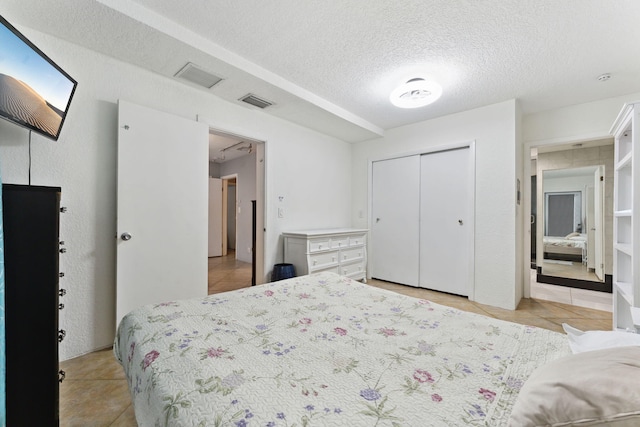 bedroom featuring light tile patterned flooring, a closet, and a textured ceiling