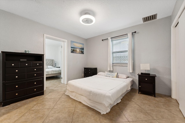 bedroom with a textured ceiling and light tile patterned floors