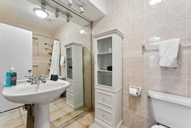 bathroom with tile walls, tile patterned flooring, curtained shower, and toilet