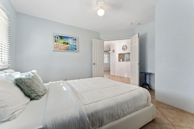 bedroom with multiple windows, light tile patterned floors, and ceiling fan