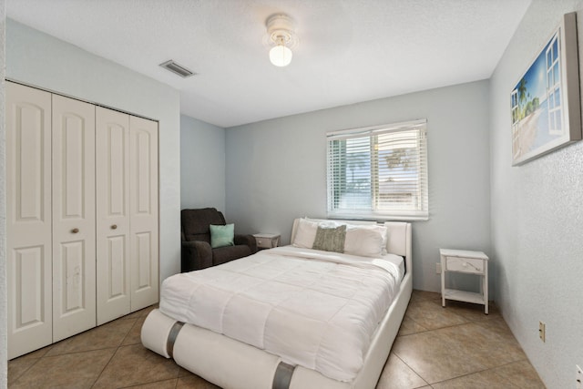 tiled bedroom with a textured ceiling and a closet