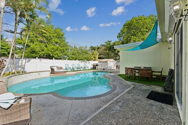 view of swimming pool featuring a storage shed and a patio area