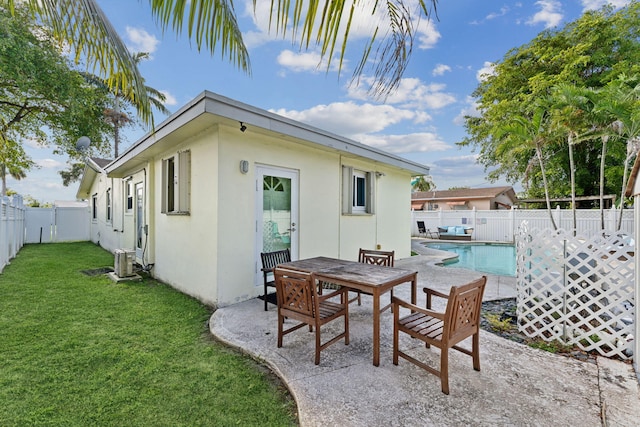 rear view of property featuring a fenced in pool, central AC, a patio area, and a lawn