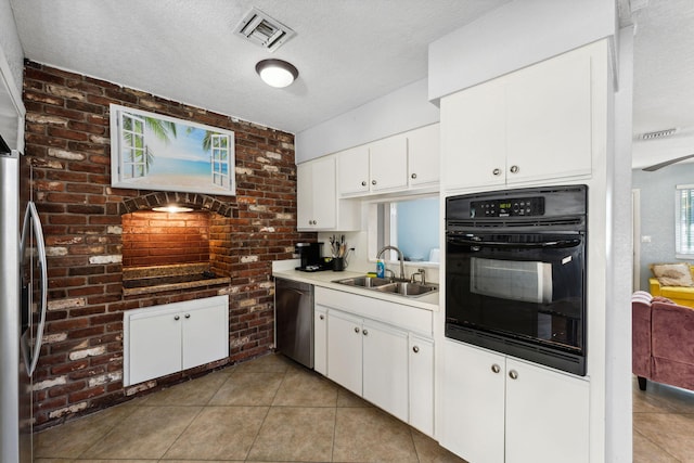 kitchen featuring sink, light tile patterned floors, appliances with stainless steel finishes, a textured ceiling, and white cabinets