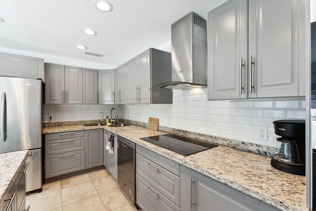 kitchen with wall chimney range hood, gray cabinetry, stainless steel appliances, light stone countertops, and decorative backsplash