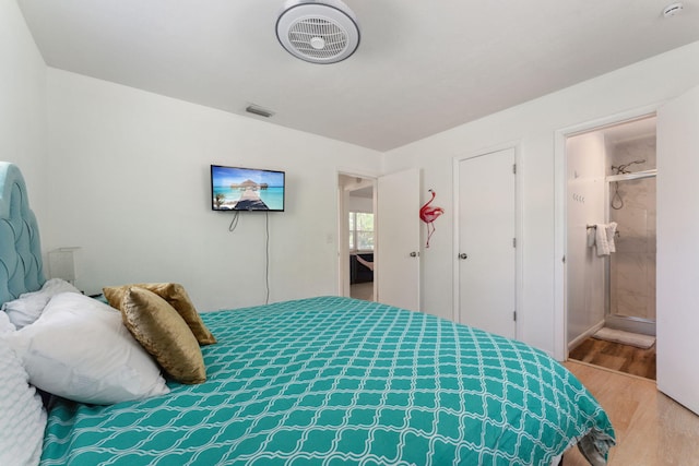 bedroom featuring connected bathroom and light hardwood / wood-style flooring