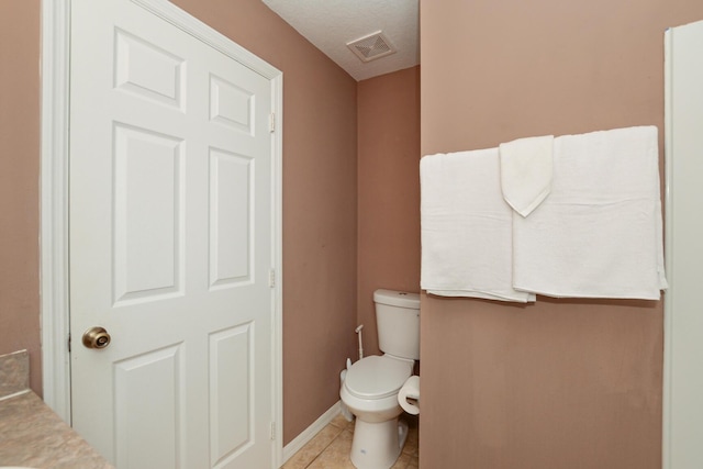 bathroom with tile patterned flooring, toilet, and a textured ceiling