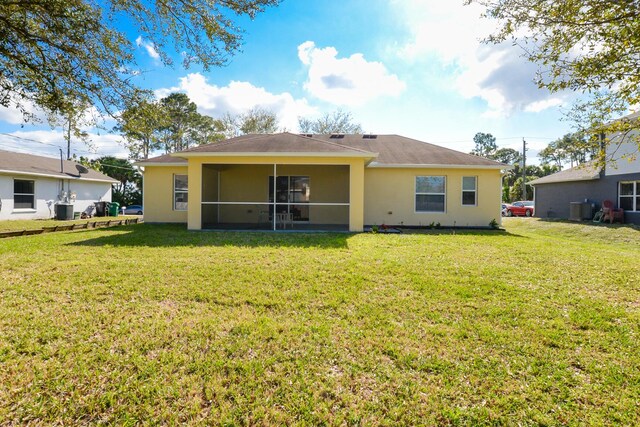 rear view of property featuring cooling unit, a yard, and a sunroom