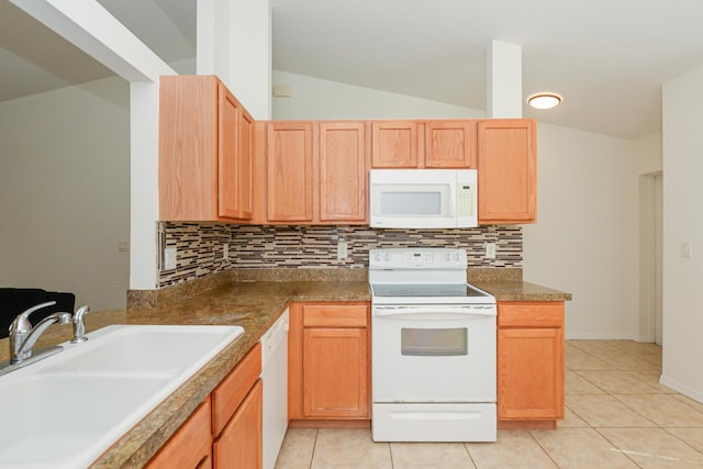 kitchen with vaulted ceiling, white appliances, sink, and light tile patterned floors