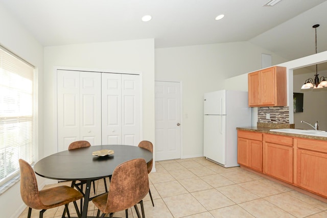 dining space featuring a healthy amount of sunlight, lofted ceiling, sink, and a notable chandelier