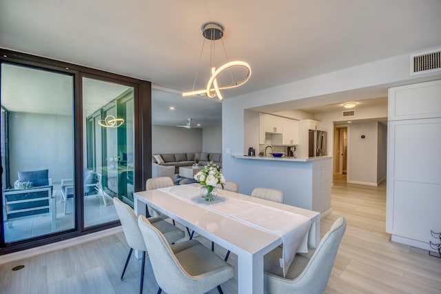 dining space with expansive windows, an inviting chandelier, and light hardwood / wood-style flooring