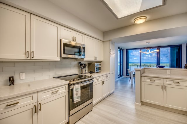 kitchen with stainless steel appliances, white cabinetry, and hanging light fixtures