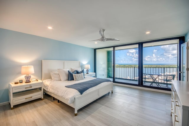 bedroom with a water view, a wall of windows, access to exterior, and ceiling fan