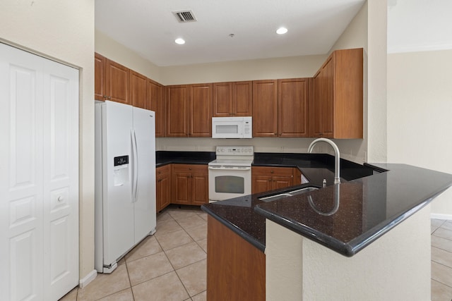 kitchen featuring white appliances, kitchen peninsula, sink, and dark stone countertops