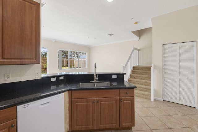 kitchen with sink, dishwasher, ornamental molding, light tile patterned flooring, and dark stone counters