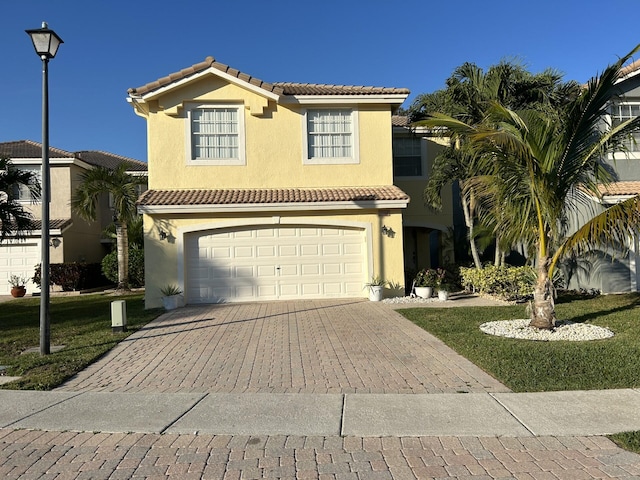 mediterranean / spanish home with an attached garage, a tiled roof, decorative driveway, and stucco siding