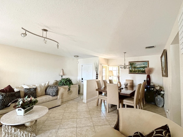 dining room featuring light tile patterned floors, a textured ceiling, visible vents, and a notable chandelier