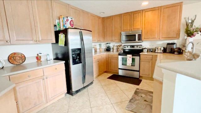 kitchen with light countertops, appliances with stainless steel finishes, light tile patterned flooring, and a sink