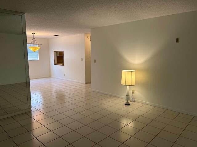 empty room with light tile patterned floors and a textured ceiling