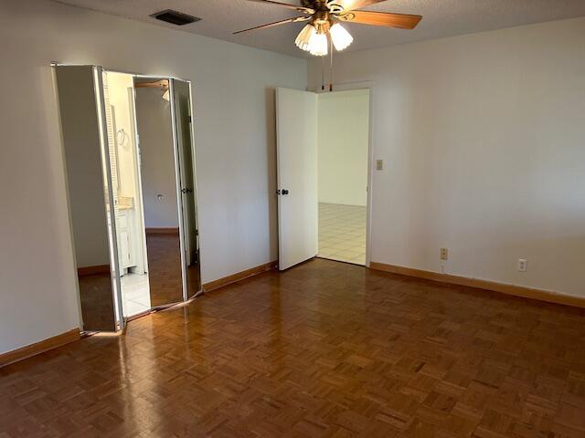 empty room featuring dark parquet flooring, a textured ceiling, and ceiling fan