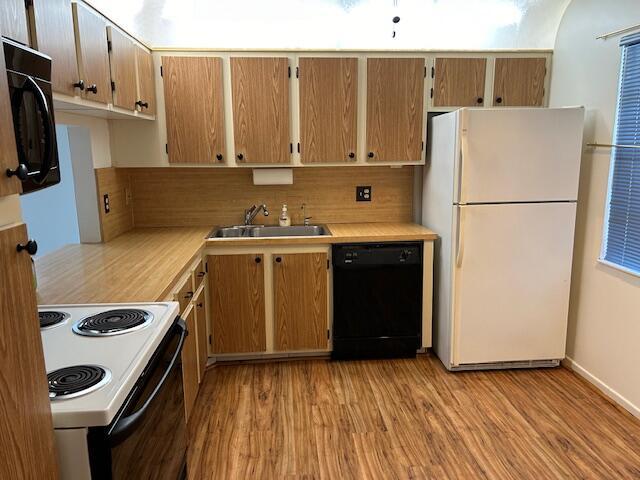 kitchen with sink, light wood-type flooring, and black appliances