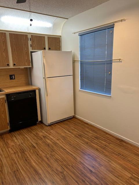 kitchen featuring wood-type flooring, a textured ceiling, black dishwasher, white fridge, and ceiling fan