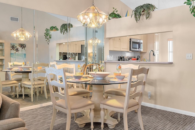 dining area with sink, a high ceiling, and a notable chandelier