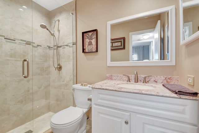 bathroom featuring vanity, a shower with door, and toilet