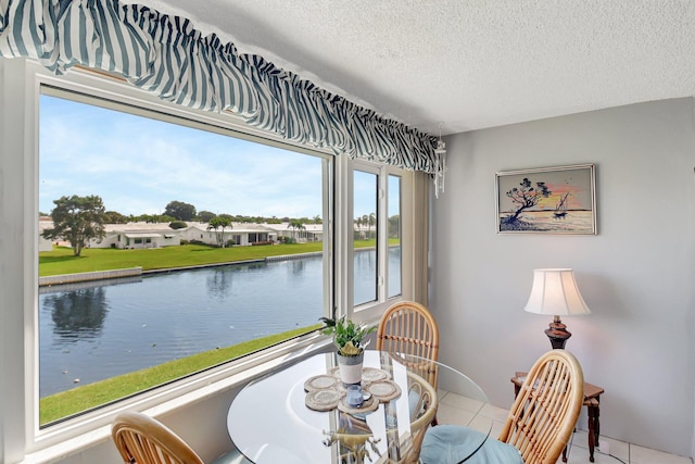 tiled dining room featuring a water view and a textured ceiling