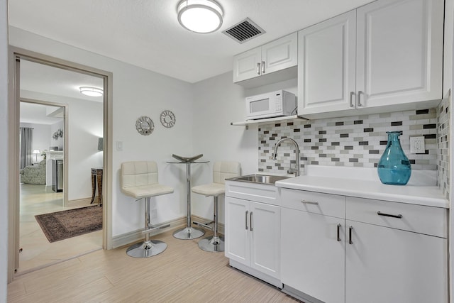 kitchen featuring white cabinetry, sink, and backsplash