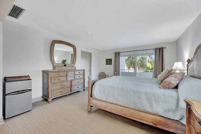 bedroom with stainless steel fridge and light wood-type flooring