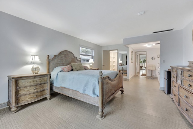 bedroom featuring connected bathroom and light hardwood / wood-style flooring