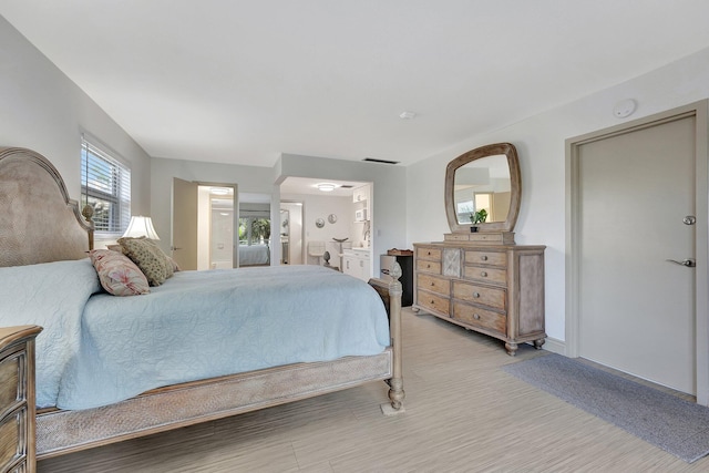 bedroom with connected bathroom and light wood-type flooring